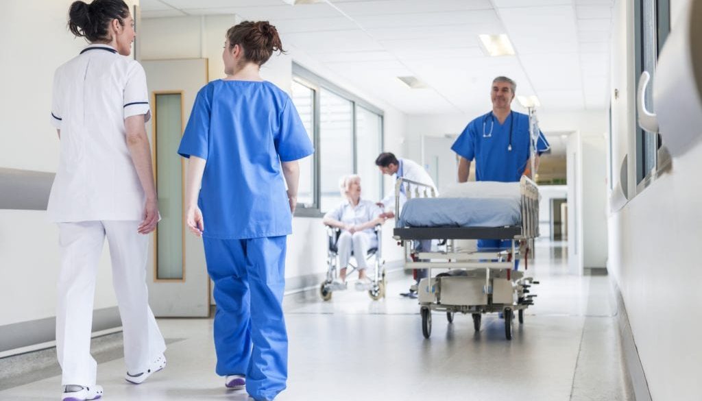 nurses walking down hallway with nurse with gurney walking other direction